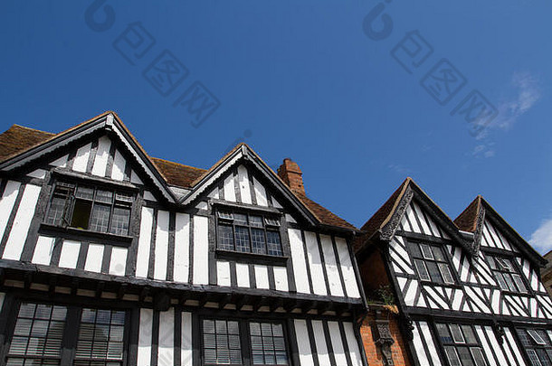 英格兰一排都铎风格的房屋，在晴朗的蓝天下有传统的黑白立面。