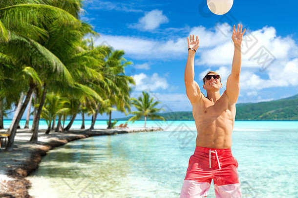 一个拿着球的年轻人在沙滩上打排球