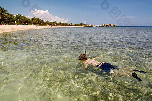 一个男孩在加勒比海岛屿的海岸边浮潜，一边在游轮上度假