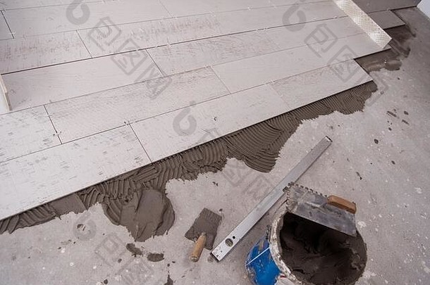 地板上的瓷砖和工具未完工铺设<strong>地板砖地板砖</strong>