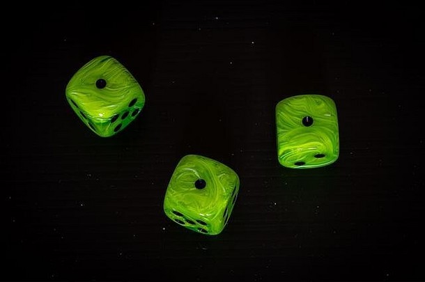 在黑色背景上玩相同数字的亮绿色骰子