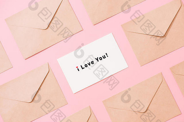 粉色桌面视图上信封和明信片的框架。我爱你的话。情人节的概念。平铺。