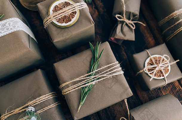 礼品和礼品用<strong>牛皮纸包装</strong>，棕色木质背景上有装饰。假日零浪费概念。