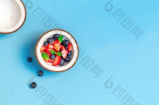 新鲜的有机浆果椰子碗光蓝色的背景健康的有机吃概念