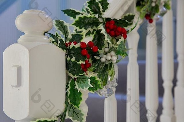 冬青树和槲寄生圣诞花环缠绕在美丽的白色楼梯周围
