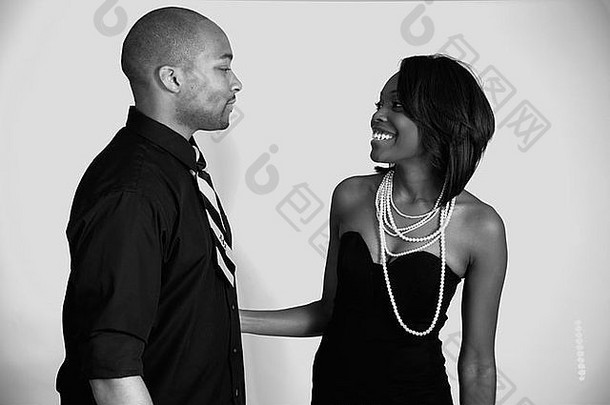 一对身穿商务装的非裔美国夫妇愉快地看着对方，脸上带着黑白相间的微笑