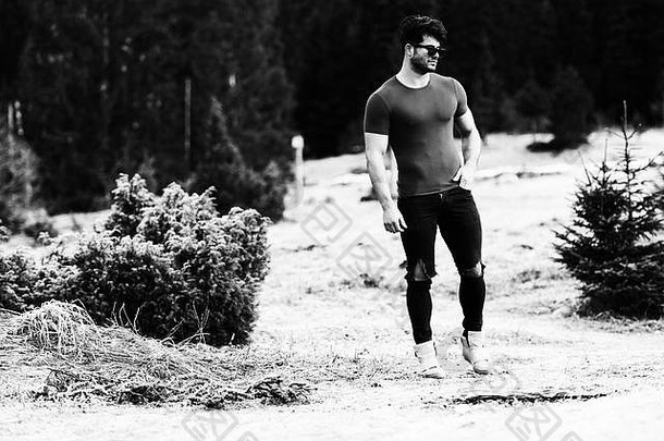 一名身体健康的年轻男子穿着黑色牛仔裤展示其训练有素的身体的肖像-肌肉发达的健美运动员健身模特