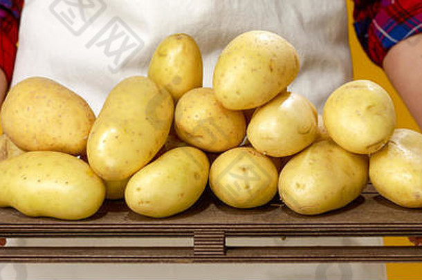 健康的食物表格特写镜头现代女人农民穿围裙孤立的黄色的显示土豆