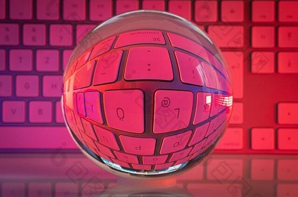 一个水晶般透明的玻璃球站在白色电脑键盘前，我们被五颜六色的灯光照亮