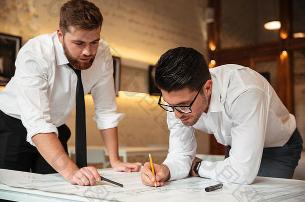 两位年轻自信的商人站在桌子边，手里拿着一张图，正在做一份商业计划书