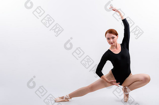 女子芭蕾舞演员在地板上摆姿势的全身照