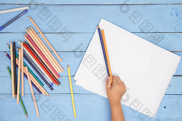 孩子们的手在蓝色桌子上用铅笔画册