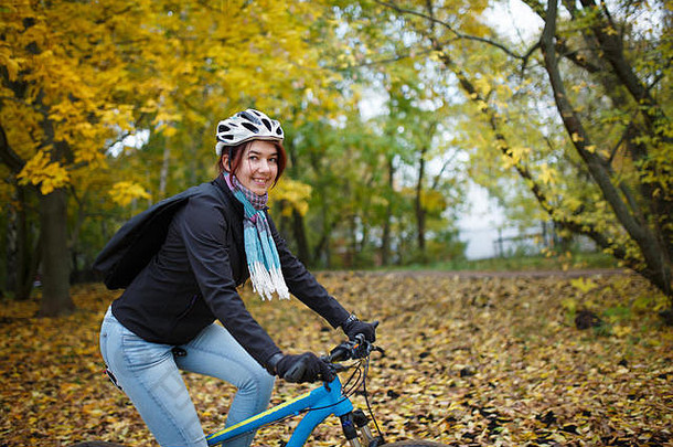 秋天戴头盔骑自行车的快乐女孩照片