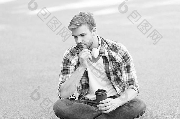 再来点咖啡。咖啡带走。那个家伙在户外喝咖啡。那个人坐在地上。戴着耳机的疲惫的学生。在线教育。听音乐。电子书概念。男式格子衬衫。学生<strong>放</strong>松和充电。