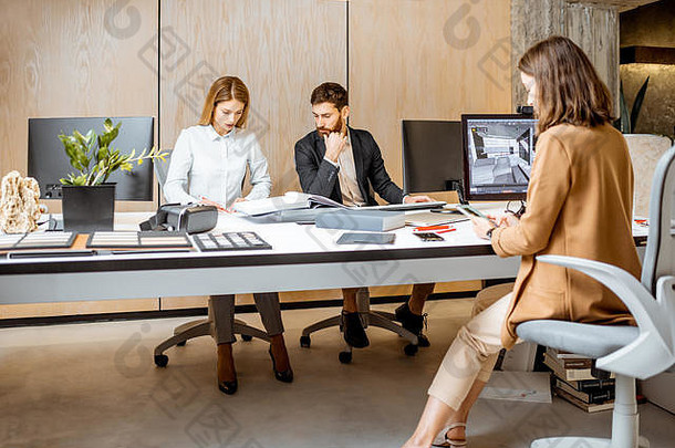 创意办公室的员工坐在建筑公司的现代办公室里，在电脑上进行室内设计。三维建模概念与数字室内设计