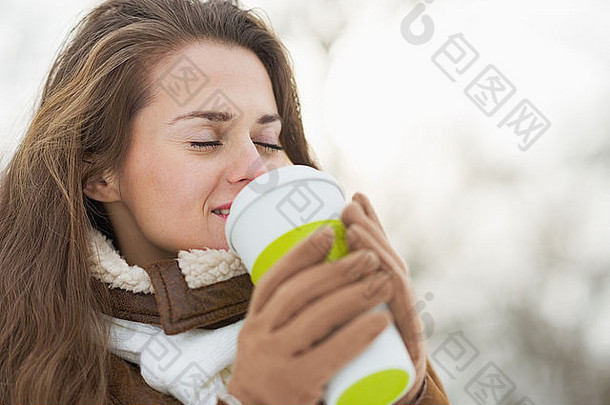 快乐年轻的女人持有杯热饮料冬天在户外