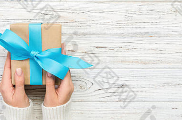 女人手给包装情人节假期手工制作的现在纸蓝色的丝带现在盒子装饰礼物白色木表格