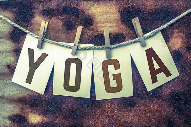 瑜伽这个词印在旧麻绳和衣夹上的卡片上，背景是生锈的古董。