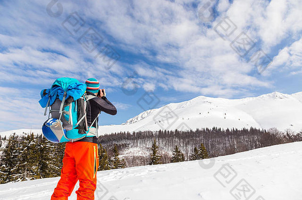 年轻的白种人摄影师在一个阳光明媚、积雪新鲜的日子里一边在野外滑雪一边谈论着照片