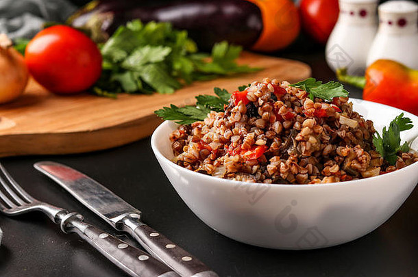 健康的荞麦和蔬菜一起放在一个白色碗里，背景为深色，是一道阿塞拜疆菜，水平方向