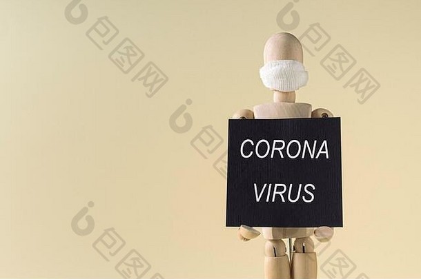 2019冠状病毒疾病传播。木制玩偶手持印有冠状病毒字样的横幅，在黄色背景上戴着面具，空白处放着文字