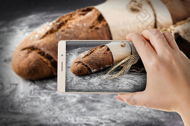 手拿着手机特写镜头。一名妇女用智能手机拍摄了新鲜烤面包的照片