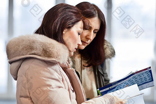 两个女商人在一个陈列室里读广告