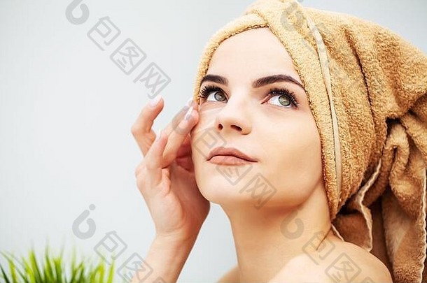 在家里，头上戴着毛巾的漂亮女人在脸上贴上补丁