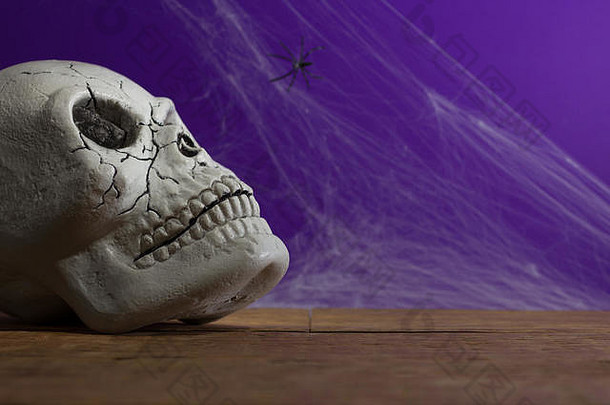 万圣节背景装饰假期概念前面视图人类头骨装饰蜘蛛网络悲观的光木表格紫色的背景
