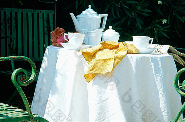 在夏季花园的天井上，用酥脆的白布在圆桌上放置白茶的特写镜头