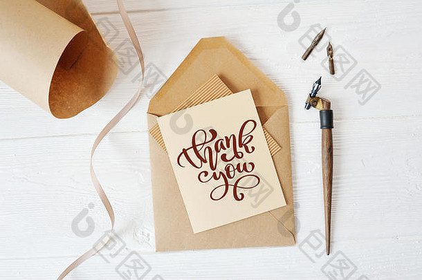 模拟节日信件空白纸和一个带钢笔的信封，放在木桌上，上面写着“谢谢”，写着“感恩节”。平铺。俯视图
