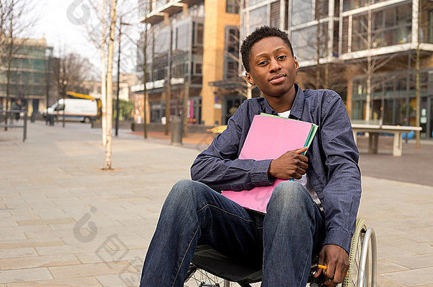 年轻的禁用学生坐着轮椅持有文件夹