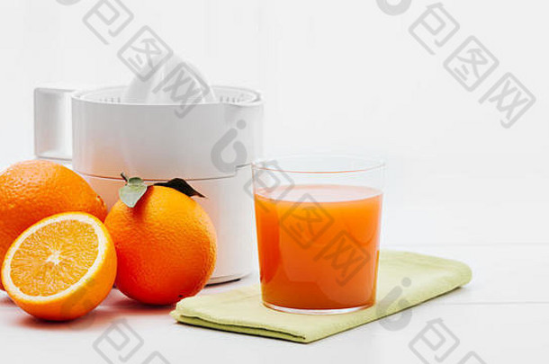 健康新鲜的果汁，榨汁机和橙子放在厨房的桌子上