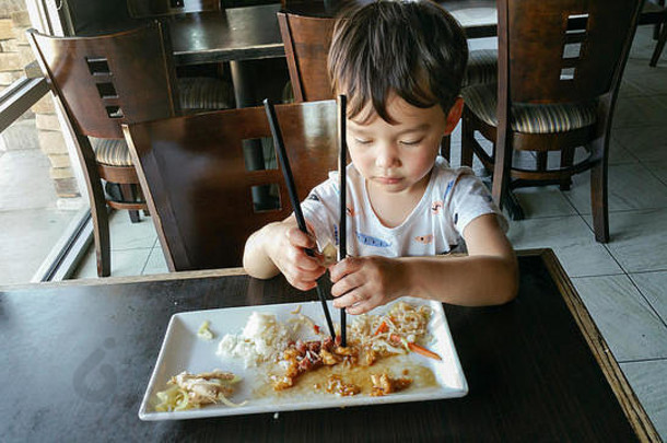 可爱<strong>的</strong>年轻中国人和白种人男孩在餐厅学习使用筷子。