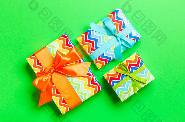 用蓝色、绿色和橙色缎带在绿色背景上的纸包装圣诞或其他节日手工礼品。礼品盒，礼品装饰