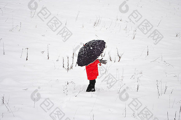 雪地里穿着红色斗篷和黑色雨伞的女孩