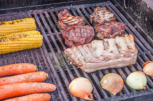 烤肉和蔬菜，包括甜玉米、胡萝卜、洋葱、猪肉弯刀、小<strong>牛肉</strong>牛排和排骨