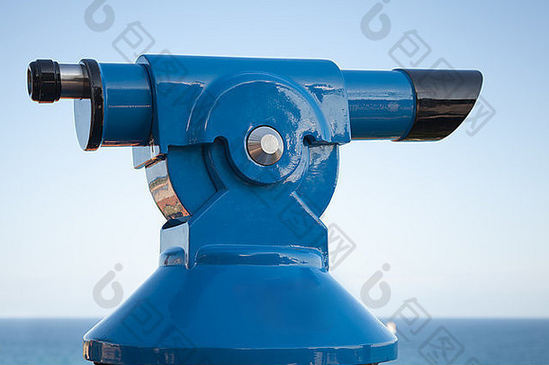 蓝色付费旅游望远镜位于蓝天背景下的海岸线上