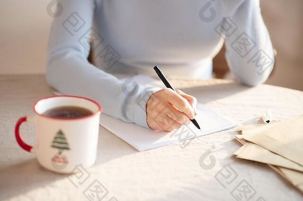 穿着灰色毛衣的女人坐在桌子旁做笔记