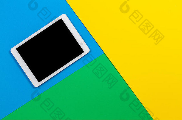 浅蓝色、绿色和黄色背景的数字平板电脑。俯视图