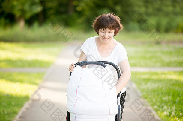 祖母在公园里带着婴儿车散步