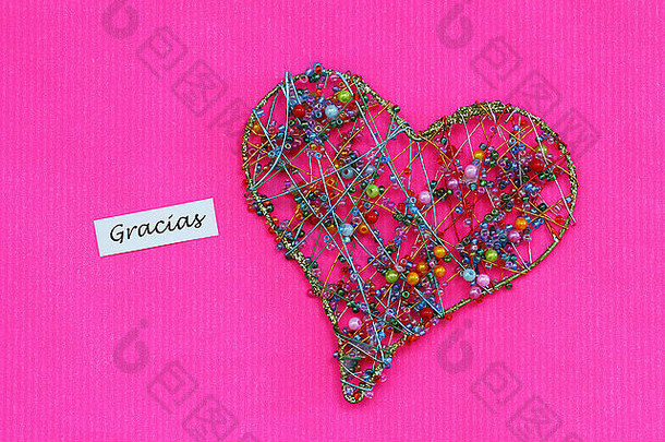 Gracias（西班牙语，谢谢）卡片，心形由彩色珠子在粉色表面制成