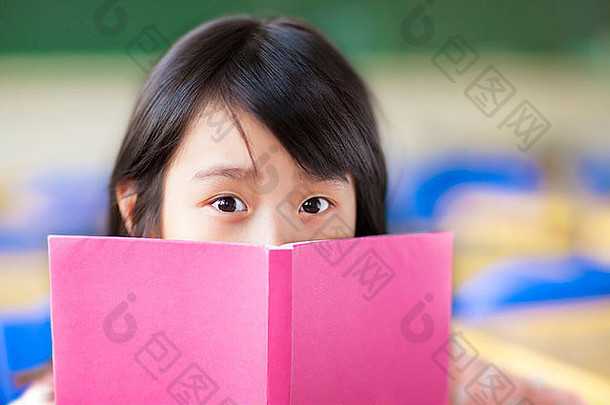 这个女孩在教室里用一本书遮住脸