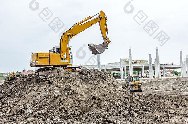 在施工现场，黄色挖掘机正在通过将地面拉到堆上的方式来堆土，<strong>项目</strong>正在进行中。