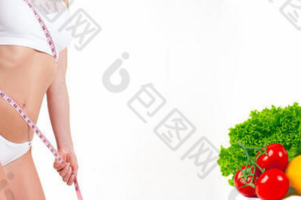 饮食观念，新鲜蔬菜和水果。一名妇女用卷尺测量她的身体