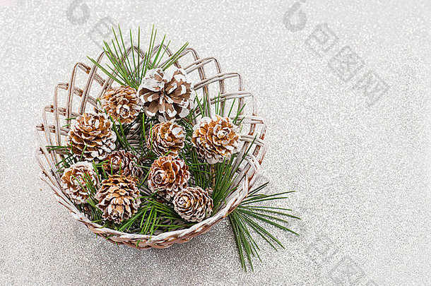 <strong>木</strong>质柳条碗中覆盖着白雪的松果，背景光亮