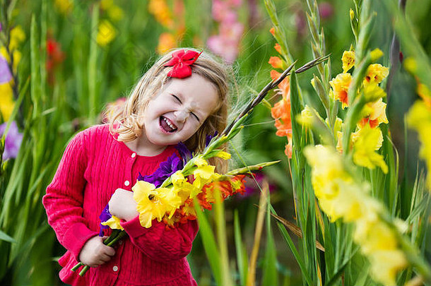 手持唐菖蒲花束的小女孩。孩子在花园里采摘鲜花。儿童秋季园艺