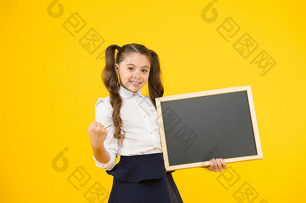 写入内存。在黄色背景上拿着黑色笔面的小女孩。小孩用粉笔板展示拳头来写信息。空白广告板，复印空间。