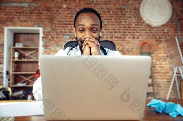 医生建议患者使用笔记本电脑上网。一位非洲裔美国医生，在与病人合作期间，解释药物的。在疫情期间为健康和拯救生命而进行的日常艰苦工作。
