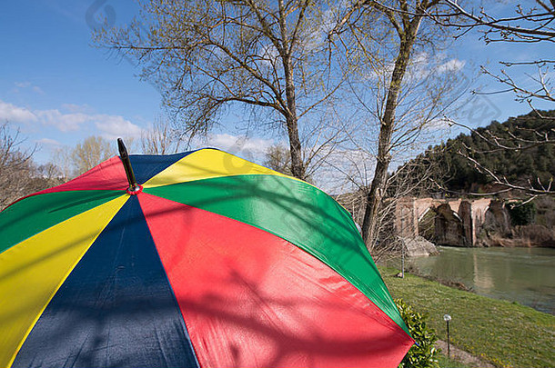 以古桥为背景的彩色雨伞。
